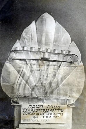 מנורת חנוכה שהכין אברהם דייגי בשנת 1944 במחנה שבויים בגרמניה. המנורה הוכנה משאריות של קופסאות שימורים שהגיעו בחבילות הצלב האדום. מתוך עיזבונו של קורפורל אברהם דייגי PAL/11020, פלוגה 602 של חיל החפרים הארץ-ישראלי – מפדויי השבי